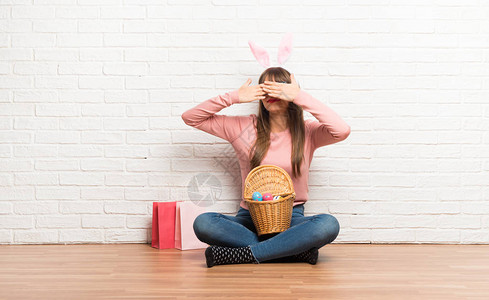 复活节时有怀兔子耳朵的妇女坐在地板上图片
