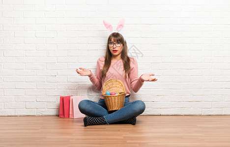 复活节时有女兔子耳朵的妇女坐在地板上图片