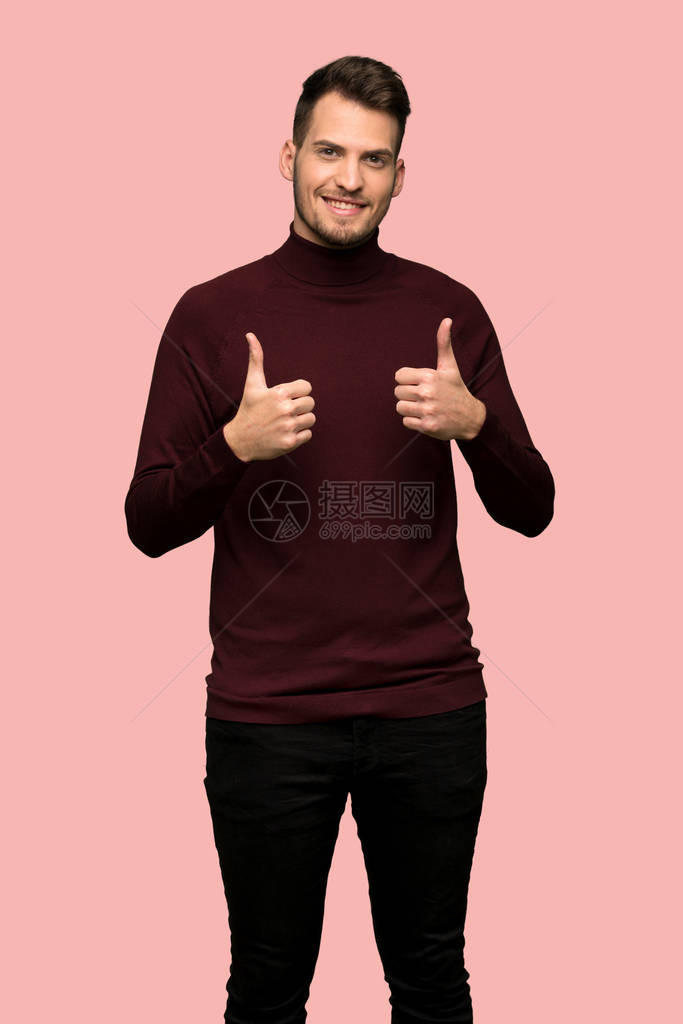 穿着上衣和大拇指的毛衣的男人因为粉红背景发生了一件好事图片