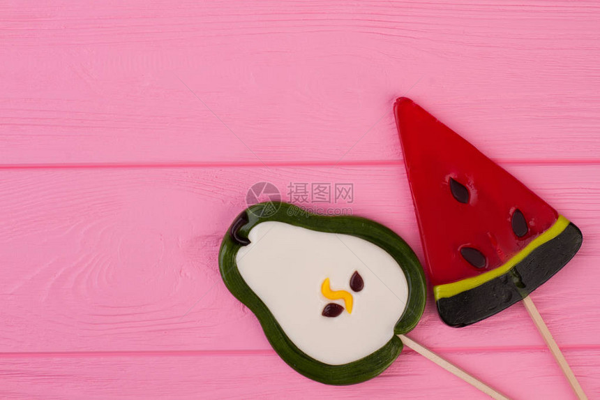 在水果形状的大鲜美棒糖梨和西瓜形状的美味棒糖带有复制空间的粉图片