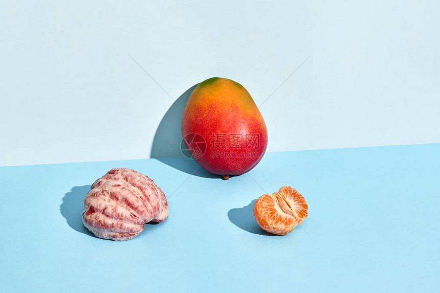 新鲜水果芒果和普通话一半带皮的曼达林和蓝底芒果的成图片