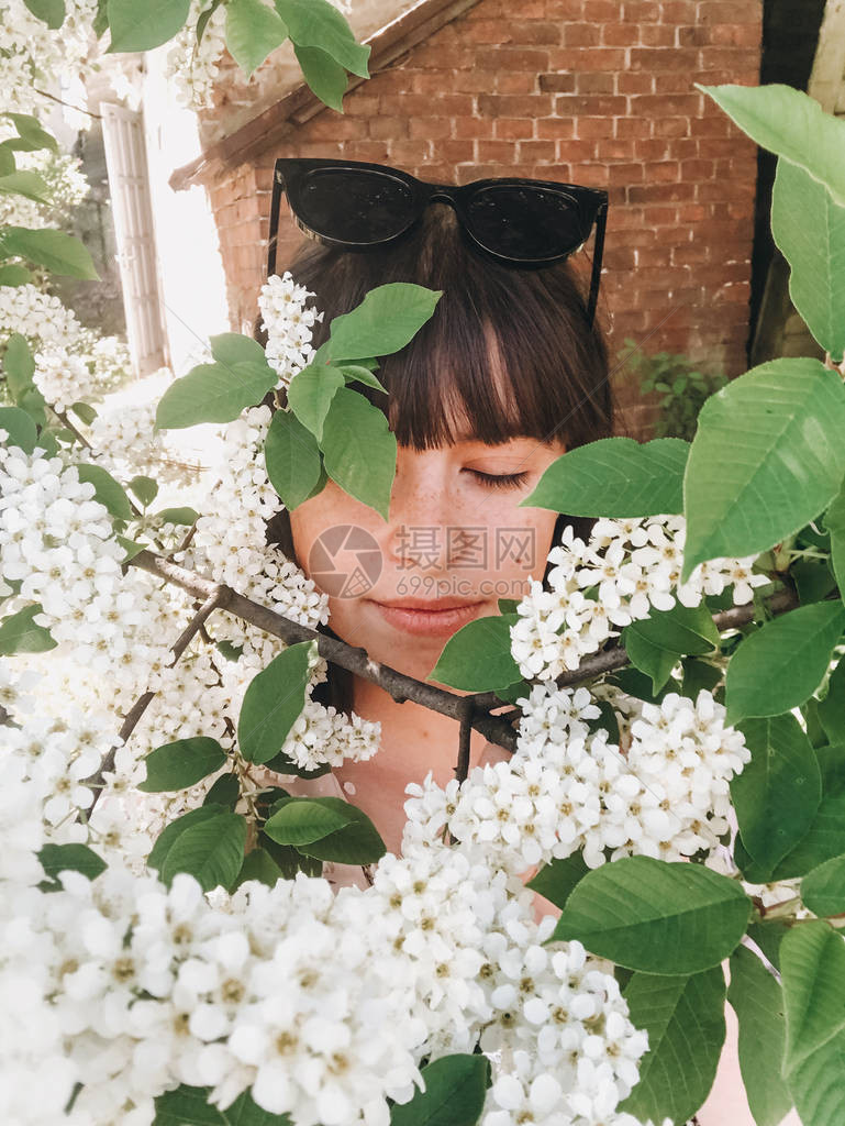 时髦的波霍女孩在鸟巢树绿枝上拿白花自拍图片