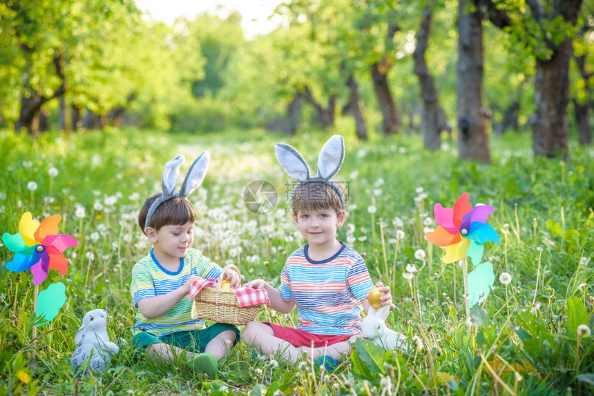 两个快乐的男孩在复活节猎后坐在草坪上图片