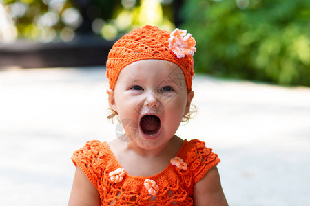 穿着橙色编织裙和帽子的女孩感到惊讶欢乐尖叫哭喊举起手来图片