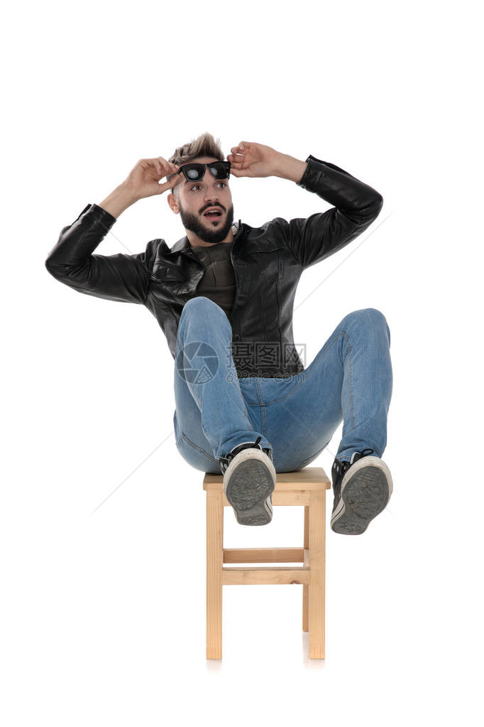 穿着黑色夹克和蓝色牛仔裤的男人从椅子上掉下来但把太阳镜贴图片