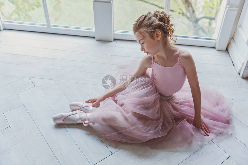 舞蹈课上的年轻古典芭蕾舞演员女孩身着粉色短裙的美丽优雅芭蕾舞女演员在白光大厅的大窗户附图片