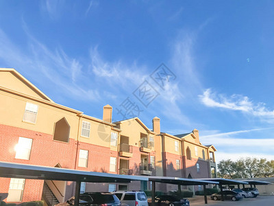 美国德克萨斯州路易斯维尔的公寓大楼和停放的汽车云天日落时带顶棚停车场的多层出租房图片
