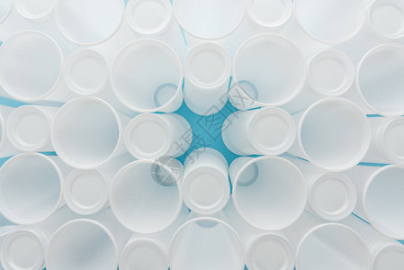 蓝色背景的白色塑料杯顶部视图图片