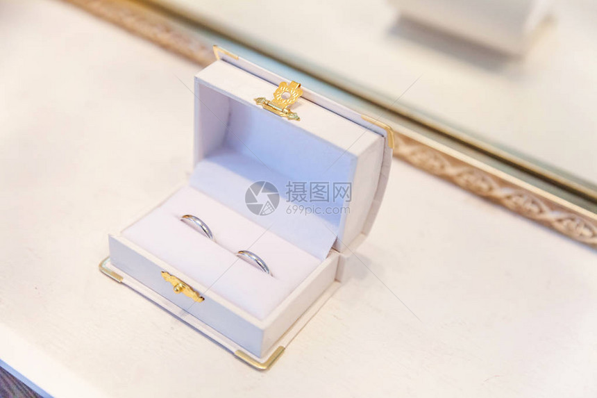 浅色背景上的白色首饰盒上的两个漂亮的结婚戒指爱的宣言婚礼卡情人节问候结婚戒指图片
