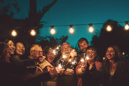 快乐的家庭在户外夜间派对上用烟火庆祝图片