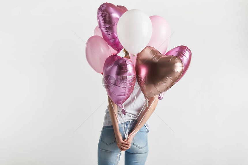 穿着牛仔布的女孩拿着心形粉红色气球的背影图片