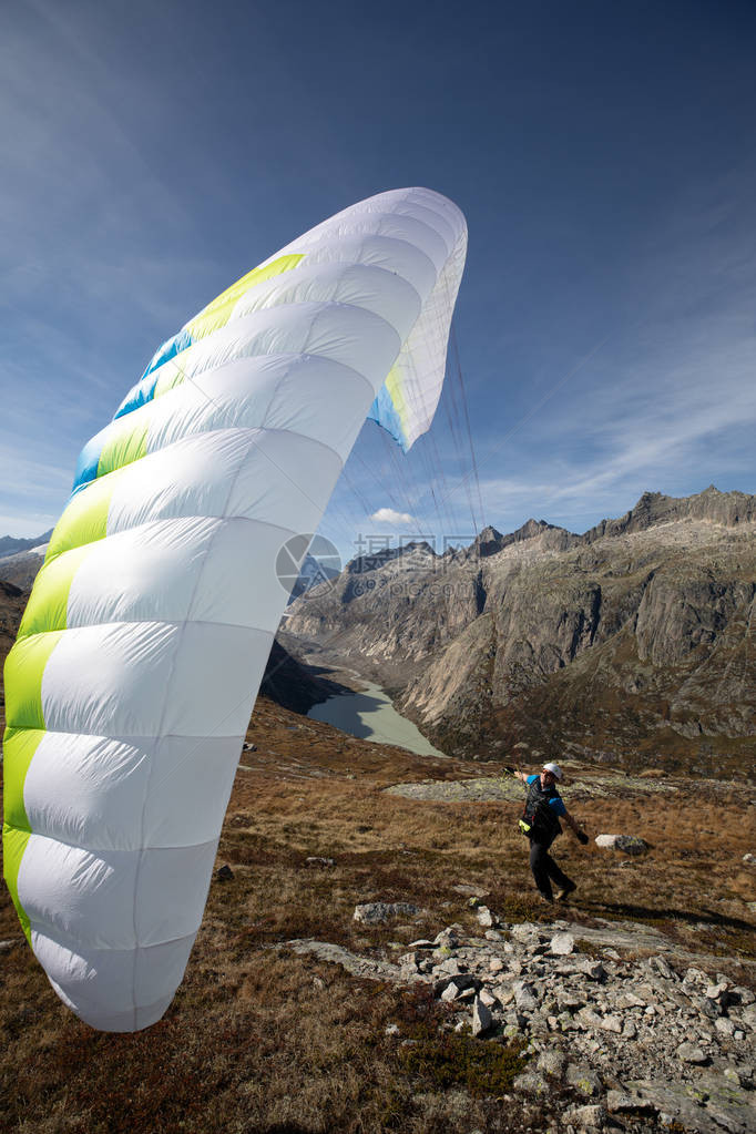 年轻的滑翔伞驾驶员利用他的滑翔机与瑞士阿尔卑斯山的风玩耍图片