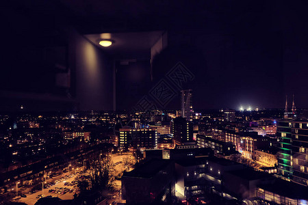 埃因霍温市的夜景从一间带灯反射的酒店房图片