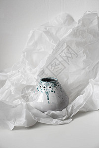 在凹痕白纸上的手工陶瓷花瓶特写日光工作室拍摄图片