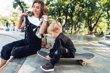 母亲和儿子在滑板上年轻母亲教她的图片