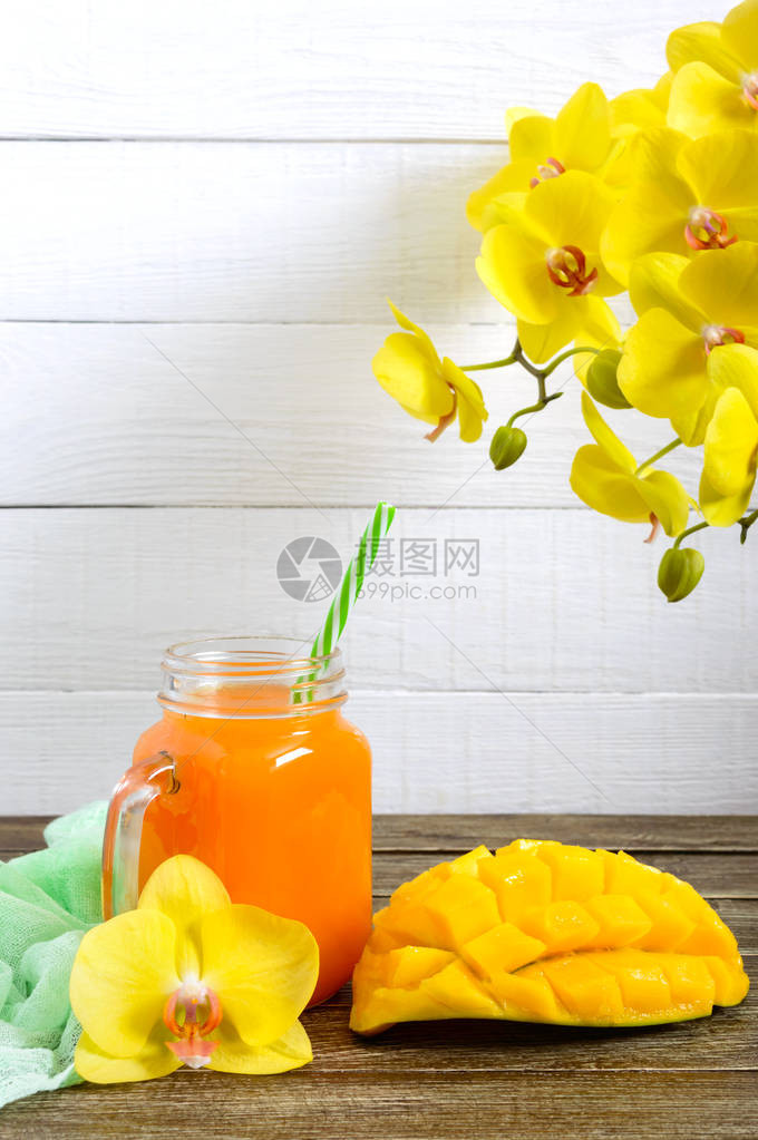 玻璃罐中的芒果冰沙和木制背景上的新鲜芒果芒果奶昔热图片