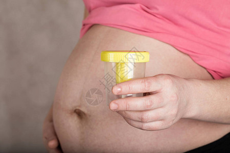 怀孕30至35岁的年轻妇女将空的尿箱放在腹部附图片