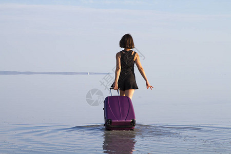 背着行李走在海里的女人的背影图片