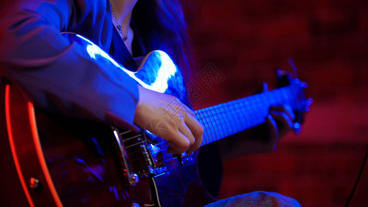 一个在霓虹灯下弹吉他的年轻女子中景图片