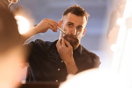 在镜子前刮胡子的大胡子男人图片