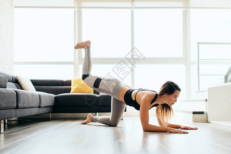 美丽的女运动员在家庭健身房训练腿部和背部肌肉时图片