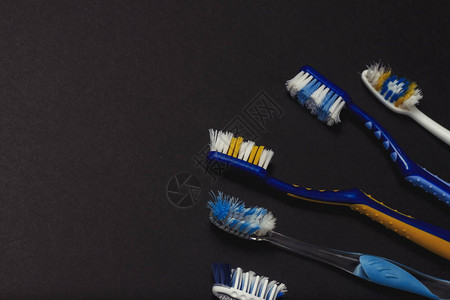 黑色背景上不同颜色的旧牙刷口腔护理概念个人卫生口腔病学平图片