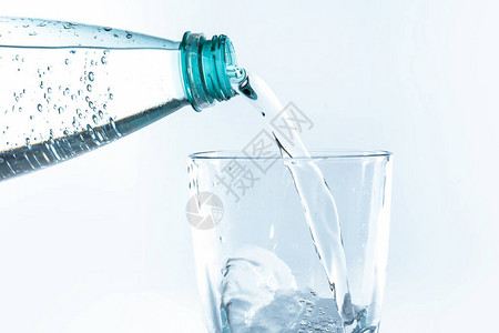 白色背景中从瓶子里倒入玻璃的水图片