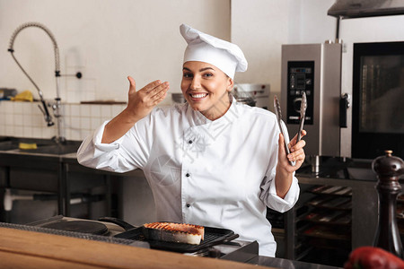 身穿制服厨的笑女厨师在厨房站着做饭美图片