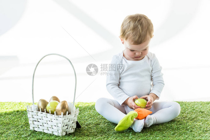 坐在草篮旁的可爱孩子带着多彩的复活节鸡蛋在图片