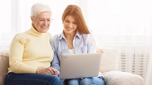 女儿和母亲在互联网上用笔记本电脑上图片
