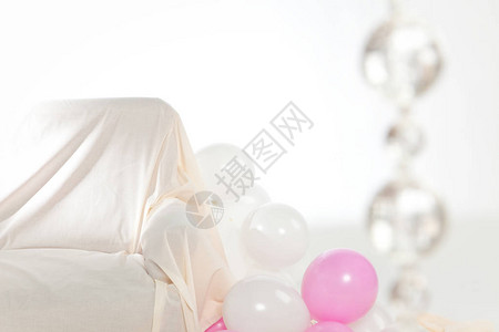 里面有白色和粉色的气球还有沙发在右边的模糊而图片