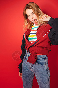 红色背景的运动夹克和牛仔裤舔棒糖时装可回到80年代90年代的新图片