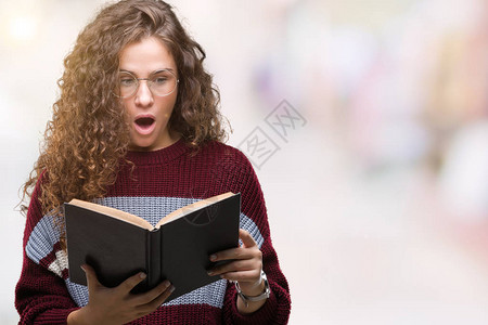 年轻的黑发女孩戴着眼镜在孤立的背景下看书图片