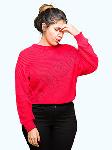 年轻美女穿着红色毛衣和包子疲惫的摩擦鼻子和眼睛感到疲劳和头痛图片
