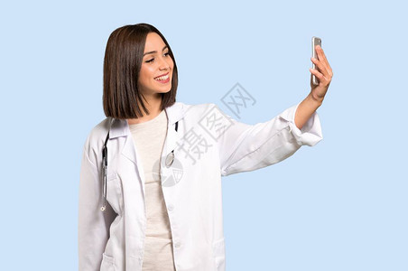 年轻女医生在孤立的蓝色背背景图片