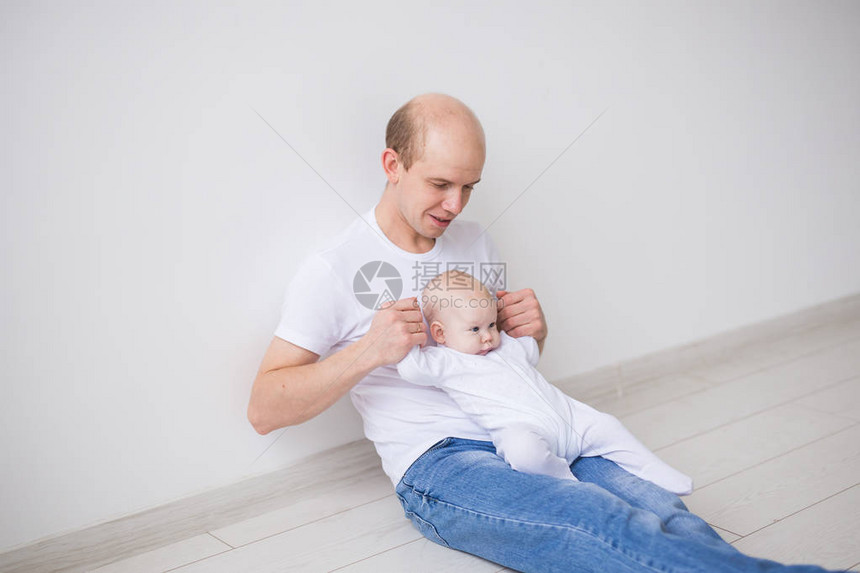 婴儿家庭和父亲的概念快乐的父亲抱着小女儿跪图片