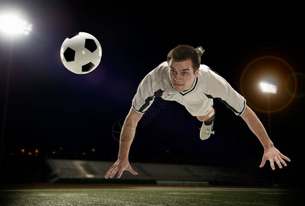 年轻足球运动员跳起球来打球时图片