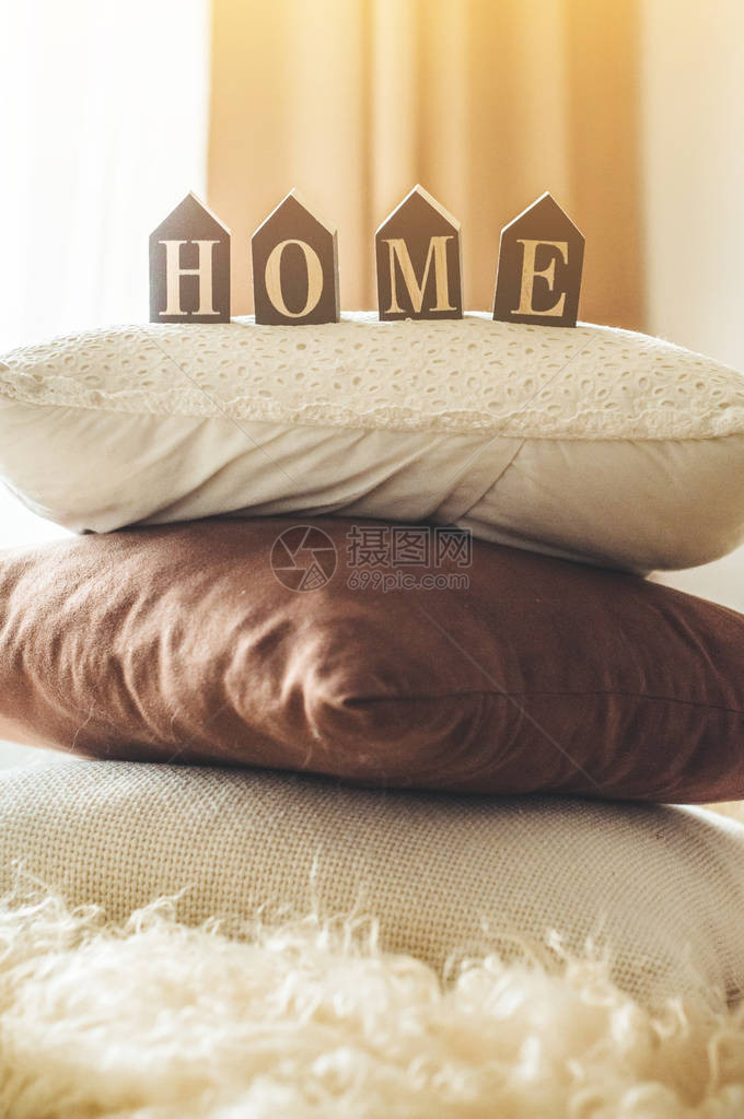 很多装饰舒适的枕头和题字HOME在床上的家庭内部在家庭内部的春图片