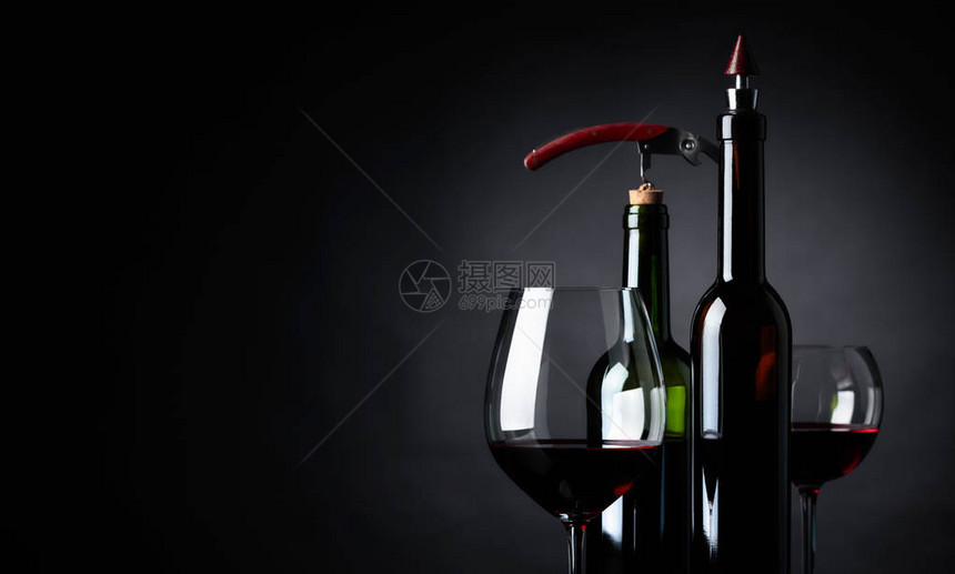 黑色背景的红葡萄酒玻璃和瓶子复制文本空图片