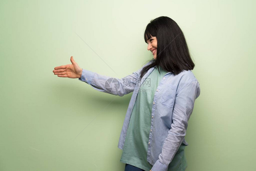 好交易后年轻女子越过绿墙握手图片