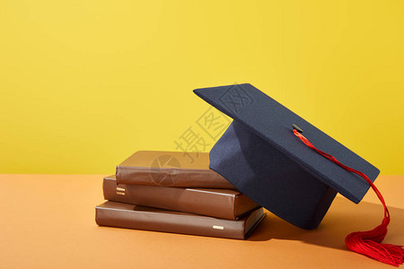 棕色书籍和有橙色表面红船的学术帽背景图片