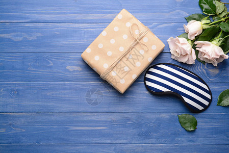 木制背景中的睡眠面具礼物和鲜花图片