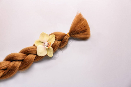 浅色背景下的编织线和花朵头发捐赠的概念图片