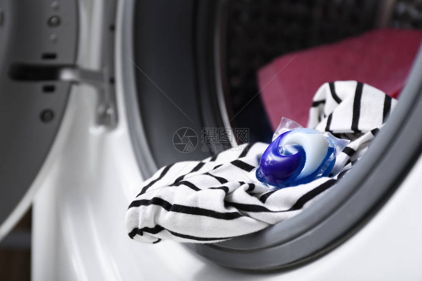 带洗衣和洗涤剂荚的洗衣机特写图片