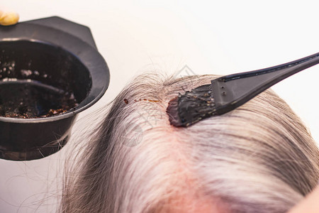 发型师将灰色头发涂成黑色在美容院的图片