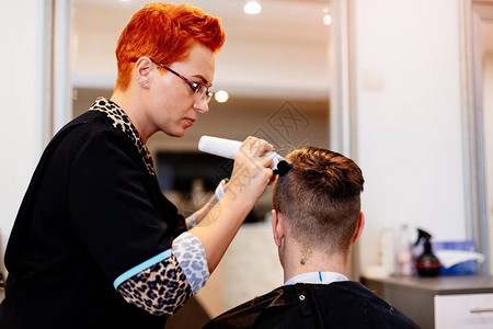 女理发师用电动修剪器男人的头发图片