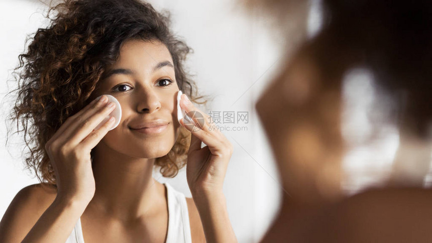 美丽的美女孩在洗手间用棉垫子照镜子擦脸图片