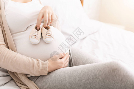 孕妇抱肚子在腹部附近拿着小鞋并复图片