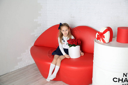 红色沙发上鲜花的美丽女孩图片