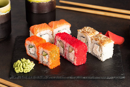 黑色石盘中的寿司卷和生鱼片图片